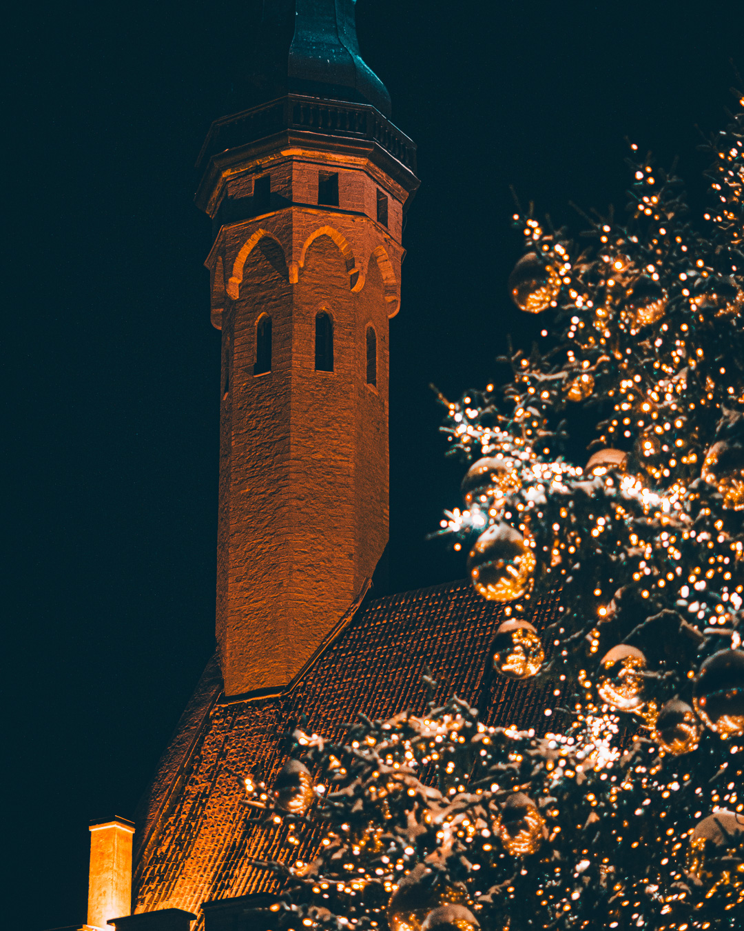 Close up of church tower with christmas tree in the foreground