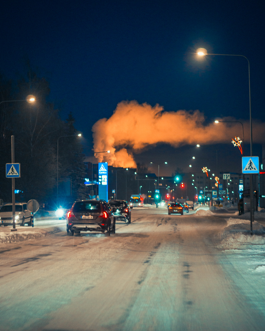 Snowy street at night with the sky lit up by orange smoke