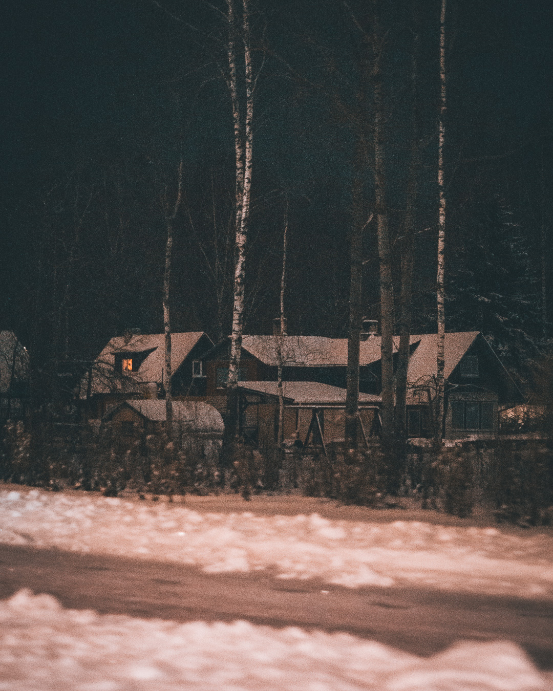 Dark countryside road with a house in the woods