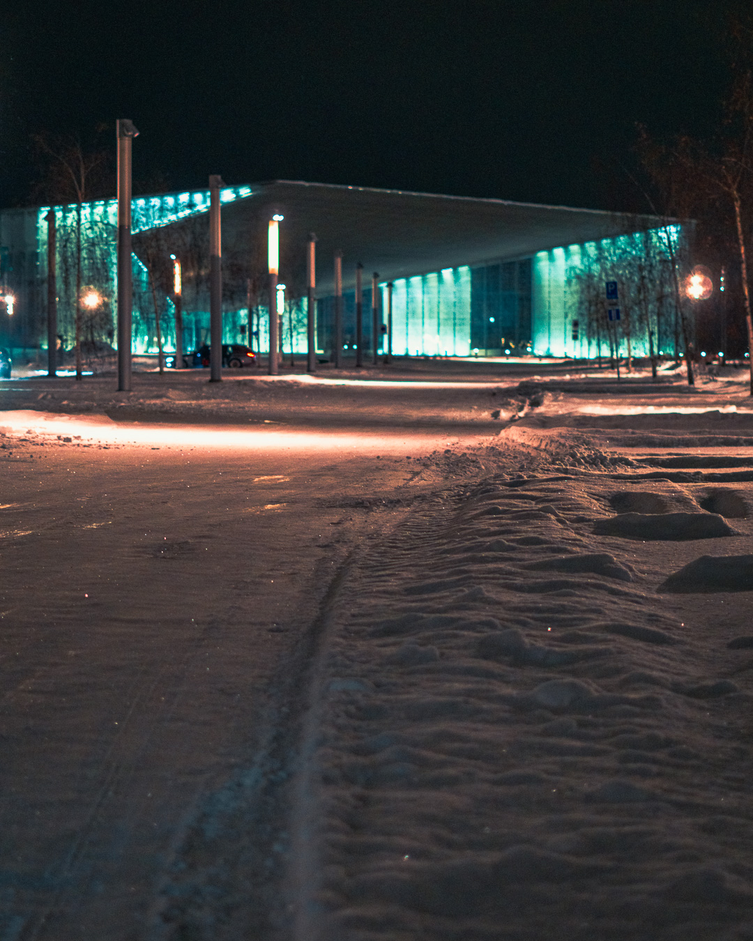 Big modern glass building in the background of a snowy road