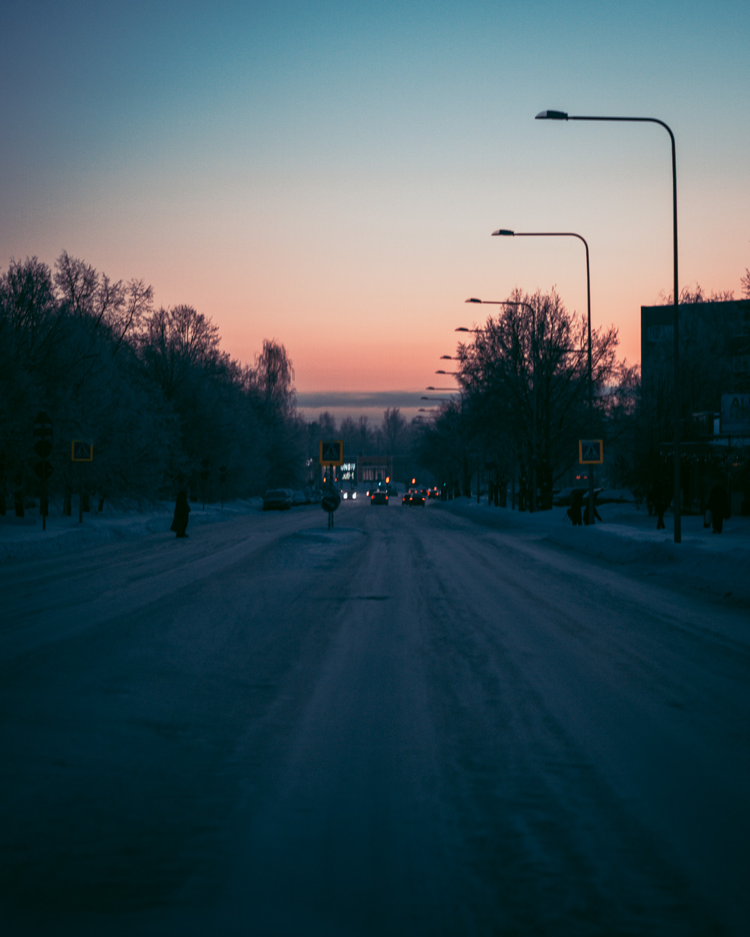 sunset in the background of a dark snowy road